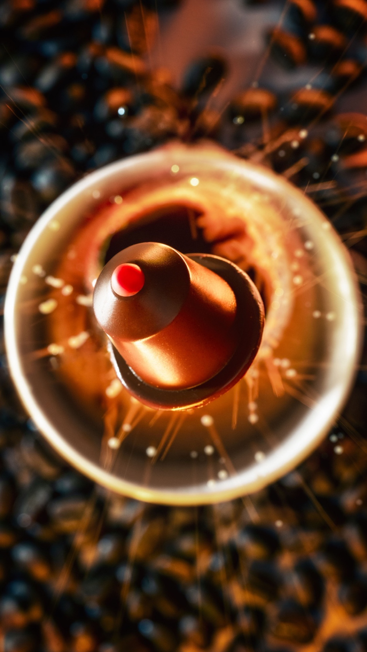 Capsule CAPSULATE cuivrée au cœur d'une tasse, sur grains de café